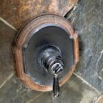 old bathroom shower valve with a wooden accent